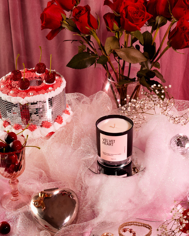 Nightwork Candle “Velvet Heart” luxury soy candle styled in a romantic still life with red roses, cherries, pink tulle, vintage glassware, and heart-shaped décor, evoking sensuality, old-Hollywood glamour, and indulgent love.
